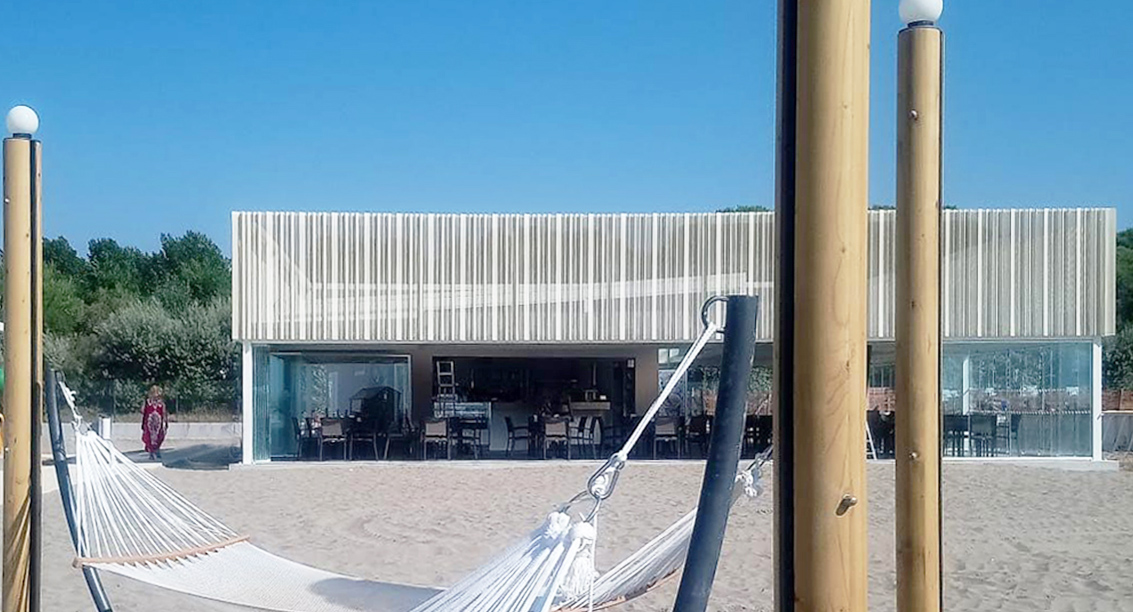 Foto di progetto di Machina Architetti Associati: Centro Servizi Spiaggia Green Oasis a Caorle. Veduta esterna ristorante. 2019